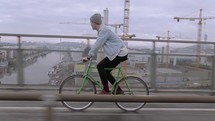 a man riding a bicycle across a city bridge 