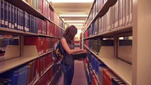 A female student looking at a book in library