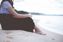 a woman sitting quietly on a beach 