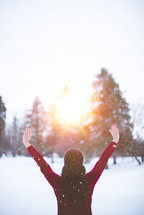 a woman standing in the snow praising God 