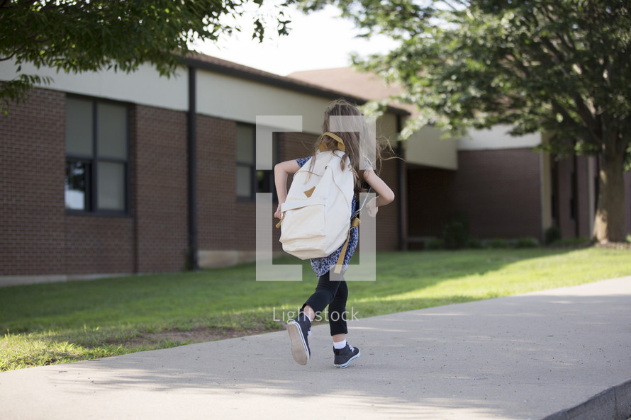 a little girl running to school 