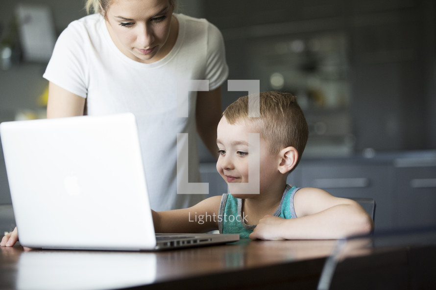 a mother teaching her son to use the computer 