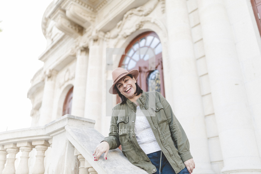 Portrait of a woman standing on the steps of a building smiling.