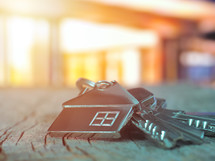 House keys with house figure on desk, out of focus background