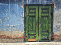 Green wooden door in an old blue building
