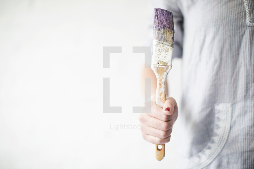 A paint brush being held by a woman.