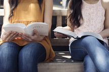 young women reading Bibles on a bench 