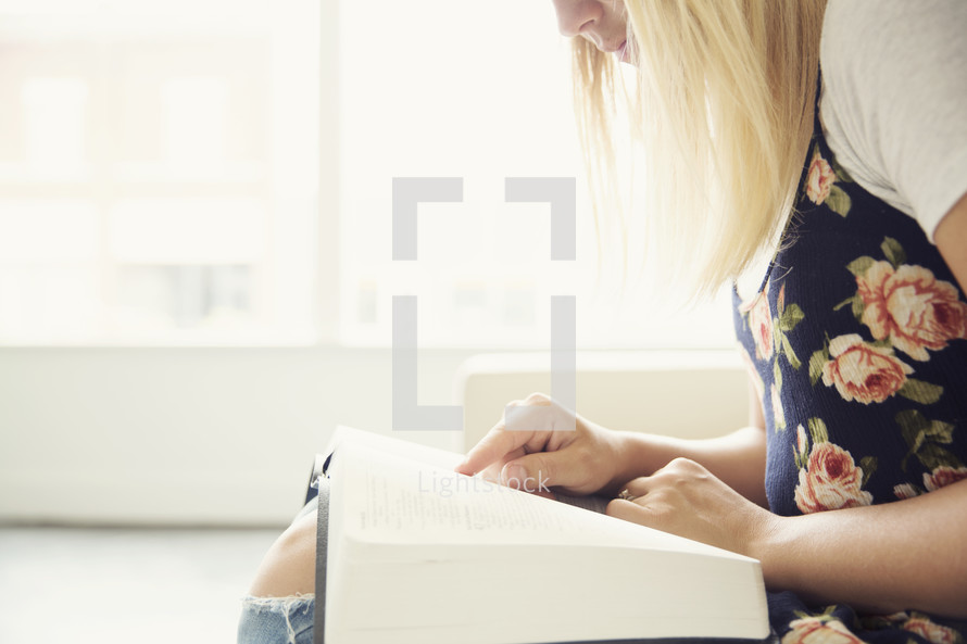 woman sitting on a couch reading a Bible in her lap 