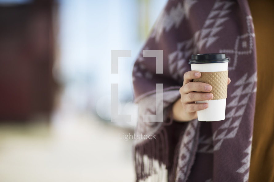 a woman in a shawl holding a coffee cup 