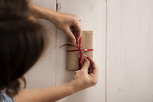 A ribbon being tied on a wrapped gift.