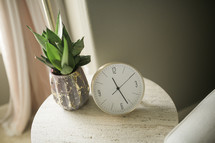 house plant and clock on a side table 