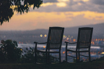rocking chairs on a hill looking out at lights below 