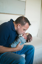  father holding a swaddled newborn baby 