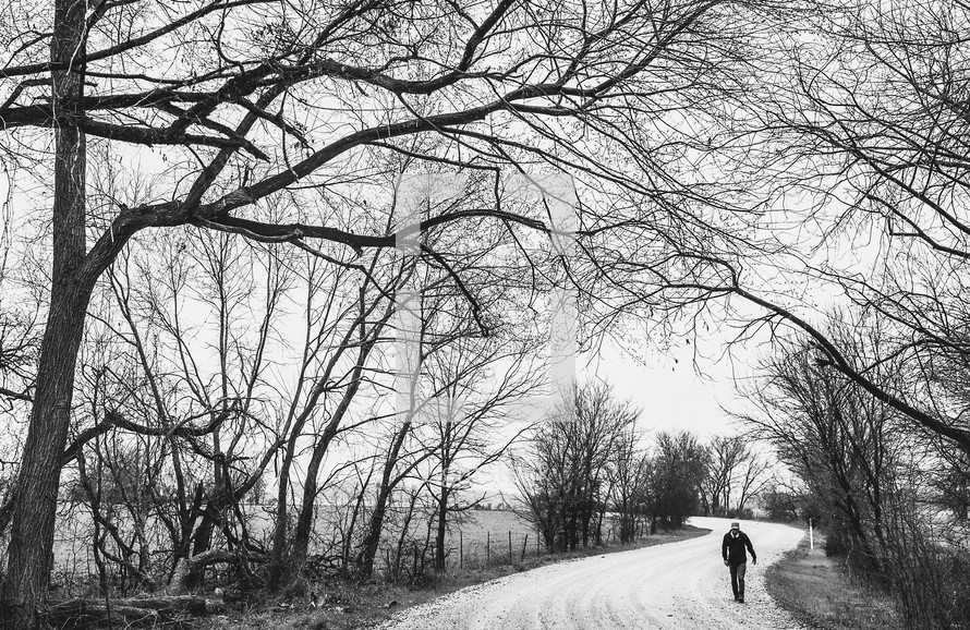 man walking down a snow covered road