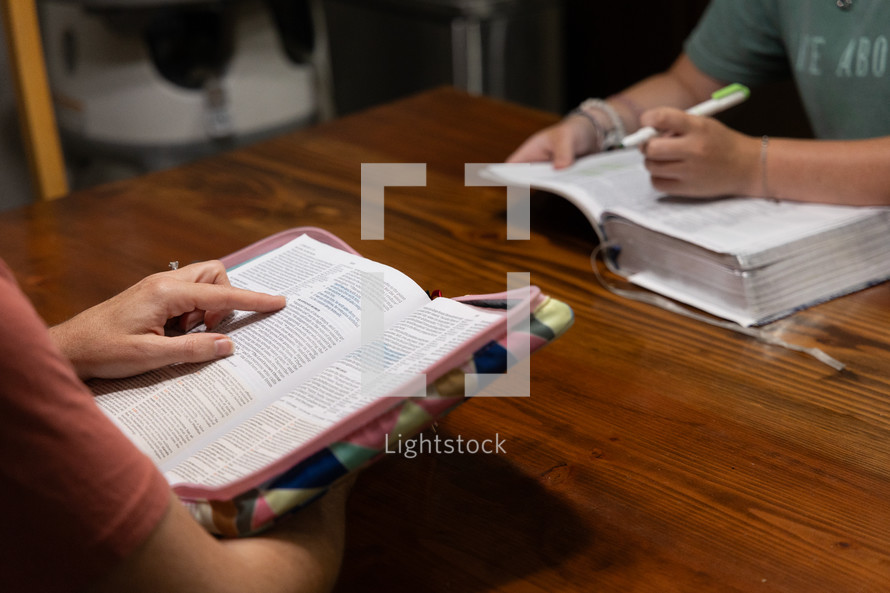 Two young women studying Bible during discipleship group Bible study, pointing and highlighting