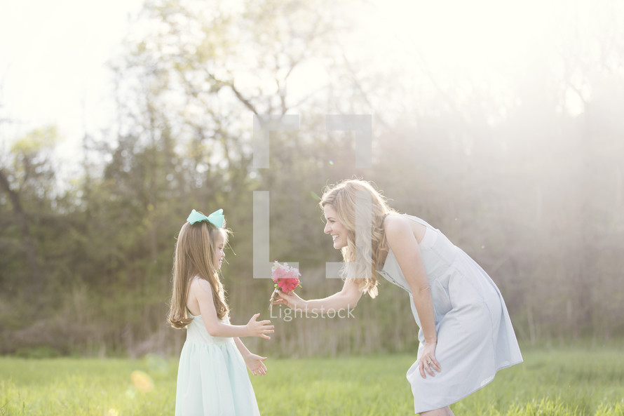 mother and daughter picking and smelling flowers outdoors 