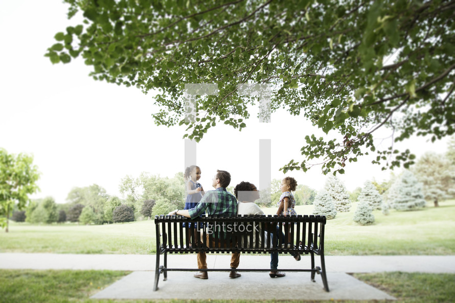 family sitting on a park bench 