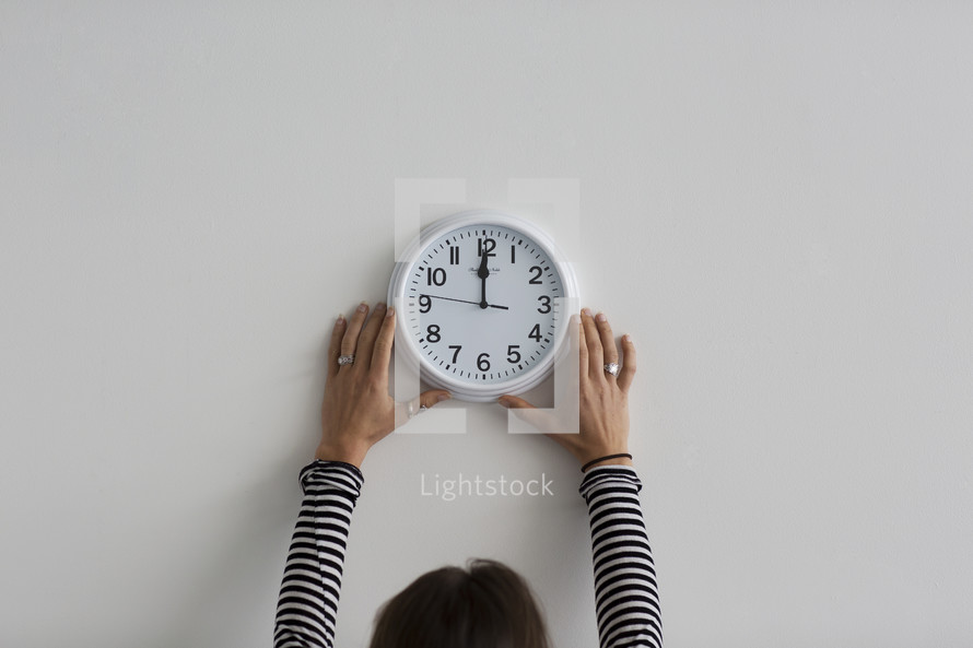 A person hanging a wall clock.