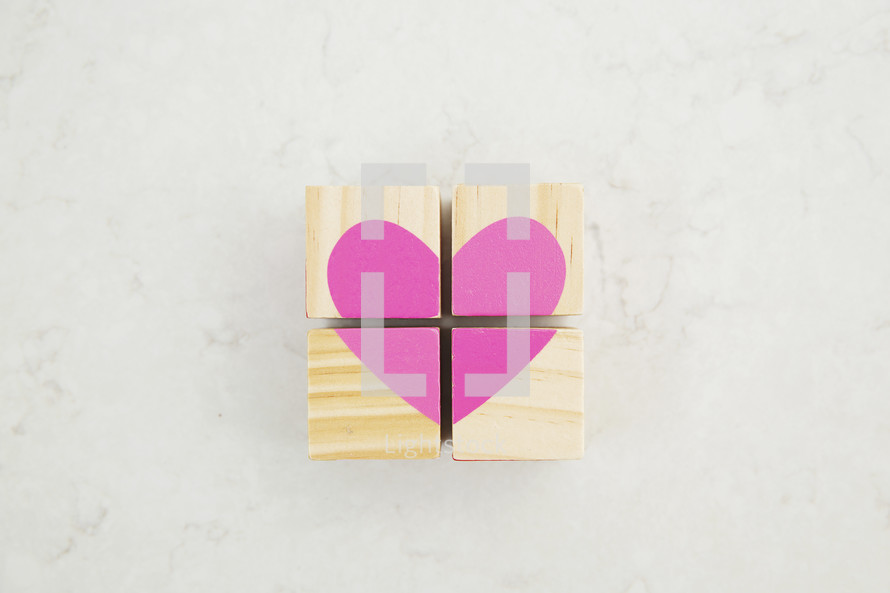 a pink heart painted on wood blocks 