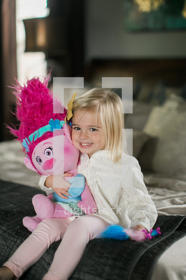 toddler girl holding a stuffed animal troll doll 