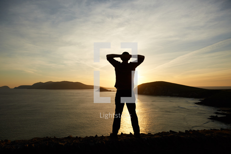 a man stretching by a shore at sunset 