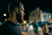 A bearded man near a crowd of people.