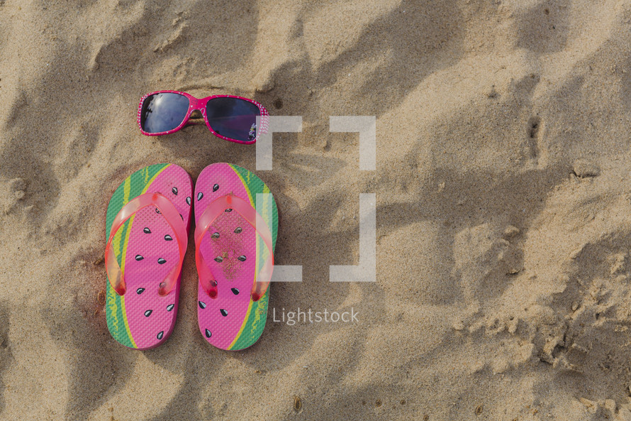 flip flops and sunglasses in the sand 