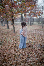 pregnant woman holding her belly outdoors in fall 
