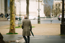 a businessman carrying an umbrella on a city sidewalk 