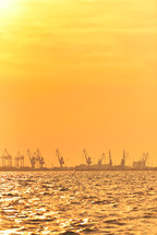 Heavy industrial port equipment, big cranes in sunset light