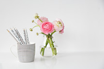 pink flowers in a vase and a mug of pencils 