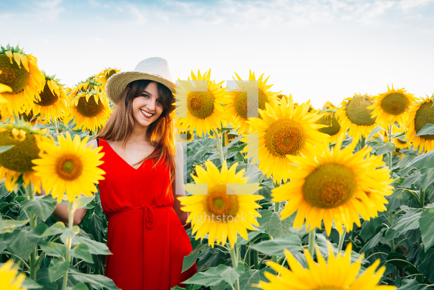 a woman in a red dress in a field of sunflowers 