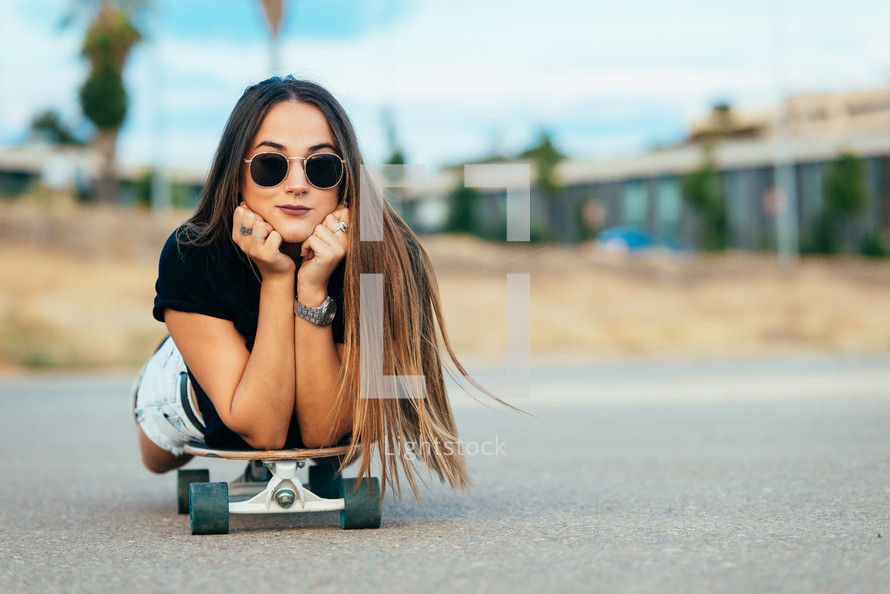 young woman lying on a skateboard 