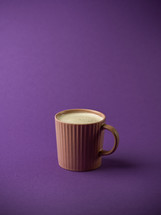 Hot drink in a pink mug on a purple background