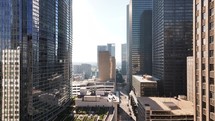 Drone view flying through misc tall buildings in downtown Houston, Texas with a sun reveal and smoke coming up from a building.