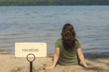 word vacation on a sign beside of a lake 