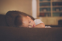 a toddler boy napping on a couch