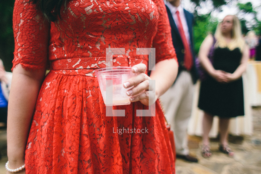 A woman in a red dress holding a drink.
