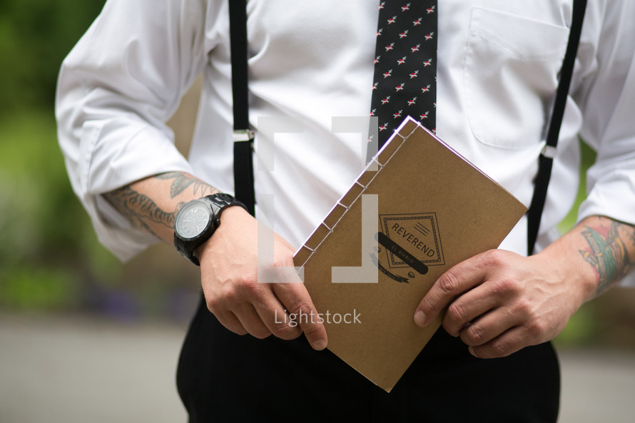 A man holding a notebook titled, "Reverend."