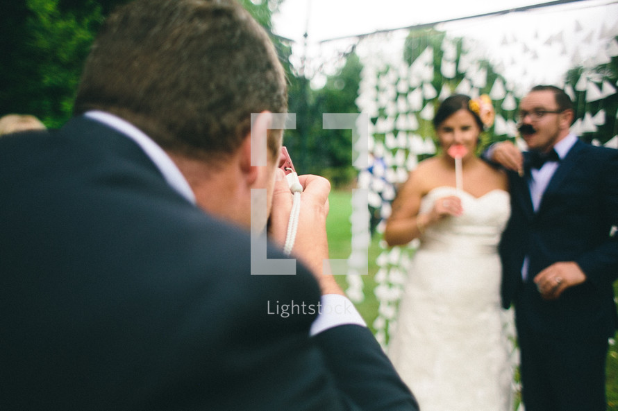 A man taking a picture of a bride and groom.