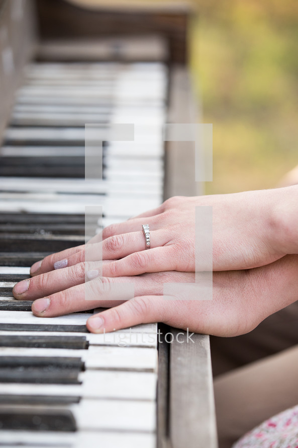 a couple with their hands on the keys of a piano 