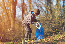   boy picks up spring forest at sunset. Environment plastic pollution