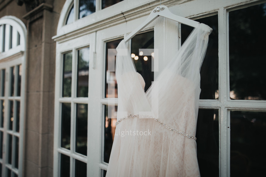 wedding dress hanging in a window 