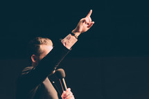a preacher holding a microphone with a raised hands 