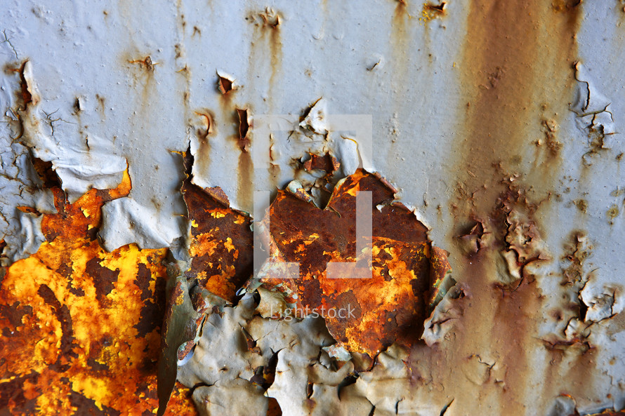 Grey paint peels to show rusted metal