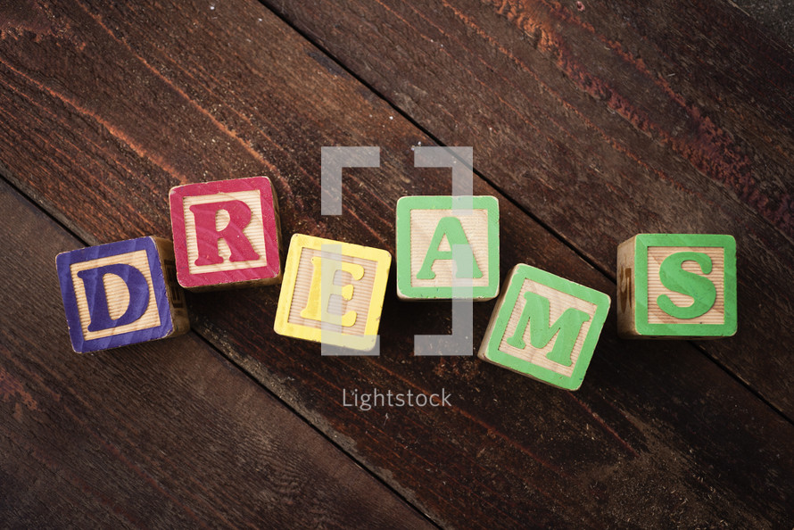 The word "dreams" spelled out with colorful wooden children's blocks.