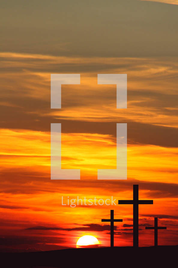Sunrise behind three crosses in silhouette 
