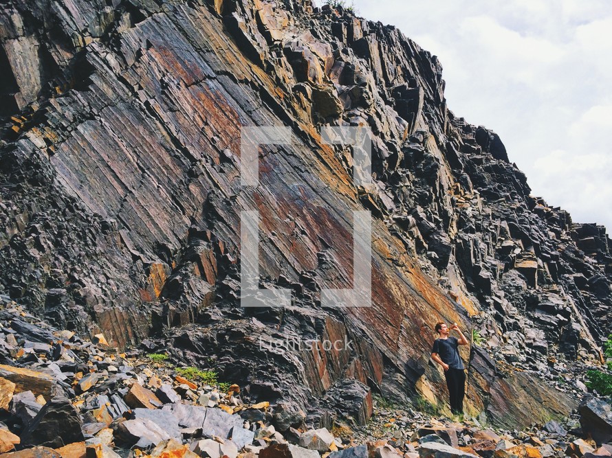 man standing beside a rocky mountainside 
