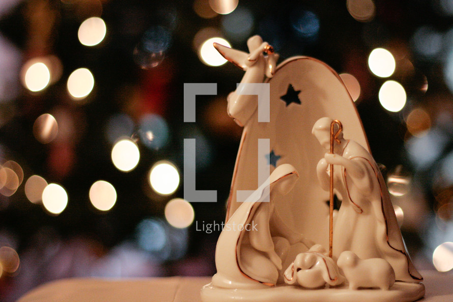 Nativity scene figurines near a Christmas tree 