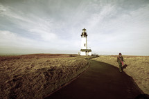 woman walking a path to a lighthouse 